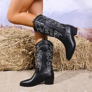 Detailopname van zwarte cowboylaarzen met een ingewikkeld wit bloemig borduursel.