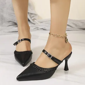 Close-up of black pointed-toe mules with elegant buckle strap and braided detail