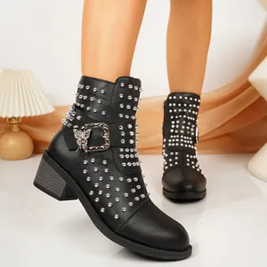 Detailopname van zwarte leren enkellaarsjes met zilveren studs en vlindergesp.
