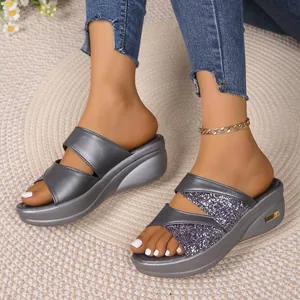 Close-up van zilveren sandalen met sleehak, glitterbandjes en plateauzolen