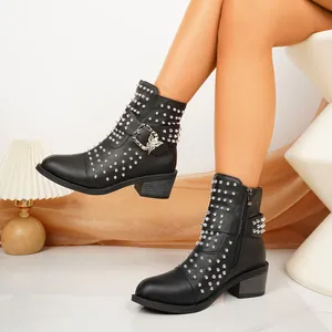 Detail van zwarte leren Chelsea-laarzen met zilveren studs en een decoratieve vlindergesp.