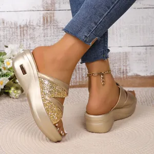 Detailopname van gouden sleehaksandalen met glitterbandjes en plateauzool voor de zomer.