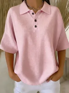 Close-up detail of the waffle-knit texture and button placket on a pink women's polo T-shirt.