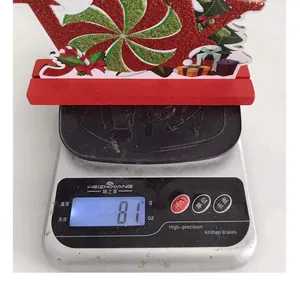 Detail view of a festive Christmas wooden ornament weighing 81 grams on a digital scale.
