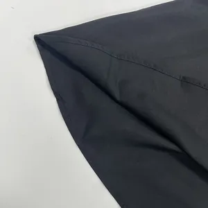 Close-up detail of the hem stitching on a black sleeveless summer camisole dress fabric.