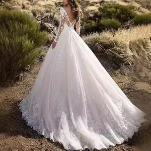 Elegant white lace long sleeve wedding dress with a floral train and voluminous skirt.