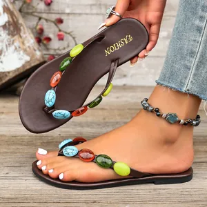 Dettaglio di infradito marroni da donna con vivaci decorazioni in pietre colorate sui cinturini