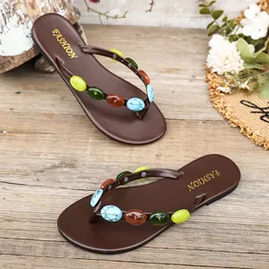 Vista dettagliata di infradito piatte da donna con cinturini decorati con pietre colorate