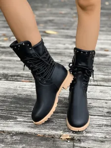 Nahaufnahme schwarzer Damen-Combat-Boots mit Nieten, Reißverschluss und Profilsohle