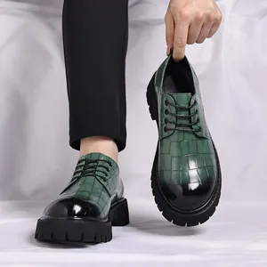 Dettaglio di scarpe stringate da uomo in pelle platform con motivo coccodrillo verde