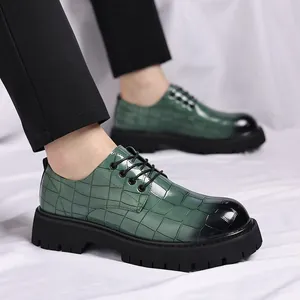 Dettaglio di scarpe da uomo verdi con motivo a coccodrillo e spesse suole nere.