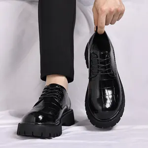 Primo piano di scarpe in pelle nera con suola spessa e dettagli con trama a griglia.