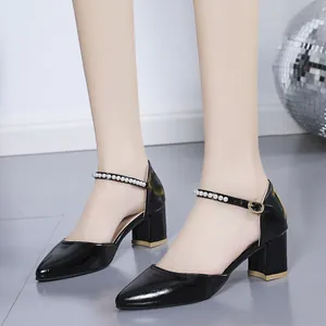 Detailed view of black patent leather chunky heels with pearl ankle strap accents