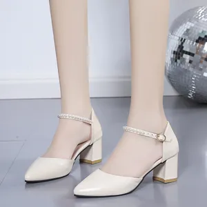 Close-up of elegant ivory pointed-toe pumps with pearl ankle strap and block heel