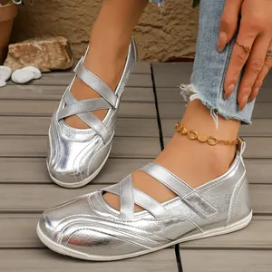 Close-up of silver metallic Mary Jane flats with criss-cross elastic straps worn on feet.