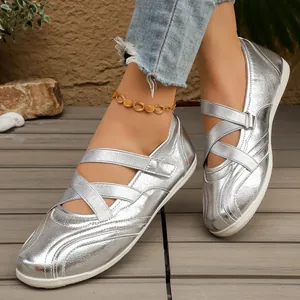 Close-up of shiny silver metallic Mary Jane flats with elastic cross straps and gold anklet.
