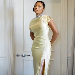 Eng anliegendes gelbes Satin-Maxikleid mit weißem Spitzenbesatz und hohem Beinschlitz