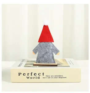 Close-up detail of a handmade Christmas gnome ornament with a red hat on a book prop