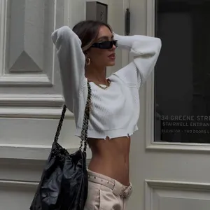 White cropped knit sweater featuring a distressed hem and long sleeves for a chic look