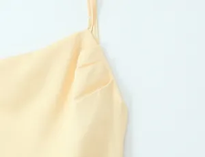 Macro detail showing the elegant pleated chest design and thin strap of a yellow dress