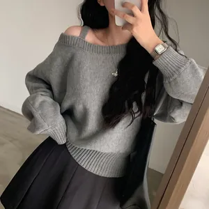 Vista dettagliata del maglione grigio con spalle scoperte e polsini a costine.