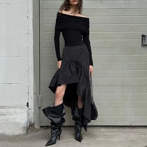 Model showcasing the flowing asymmetric ruffled hem of a black high-waisted A-line skirt.