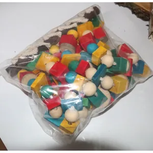 Nahaufnahme von bunten Holzblöcken und Baumwollseilen für Papageienspielzeug im Plastikbeutel.