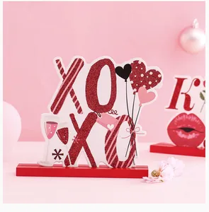 Gros plan d'une décoration de table en bois XOXO pour la Saint-Valentin, rouge pailleté.