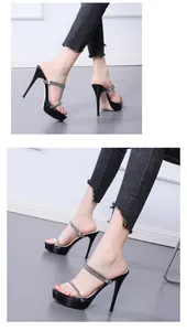 Side view of black platform sandals with rhinestones and clear straps worn with jeans