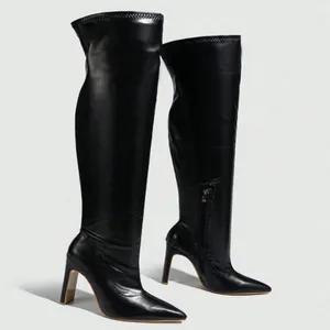 Detailansicht schwarzer Overknee-Stiefel mit spitzer Kappe, hohem Absatz und Reißverschluss.