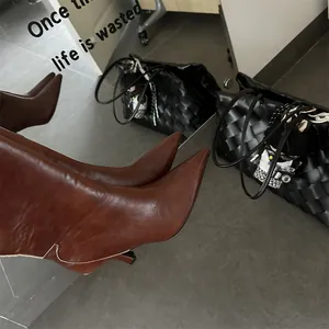 Close-up of retro brown leather stiletto boots with elegant pointed toe detail.