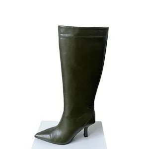 Side profile detail of dark olive green kitten heel knee-high boots on white platform.