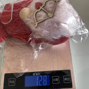 Κόκκινο πλεκτό χριστουγεννιάτικο λούτρινο ξωτικό που ζυγίζει 128g σε ψηφιακή ζυγαριά