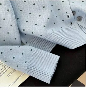 Detail view of a polka dot knit cardigan showing texture, ribbed cuffs and buttons.