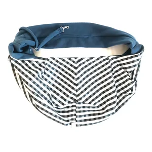 Detail view of pet sling carrier with plaid pattern and safety leash clip.