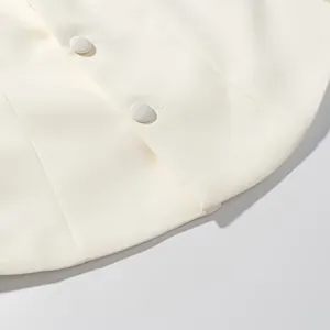 Detailed macro view of white blazer hemline featuring elegant fabric-covered buttons