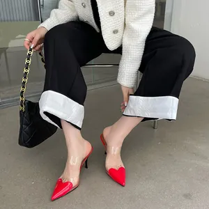 Dettaglio di eleganti sabot a punta con cuore rosso e cinturini in PVC trasparente