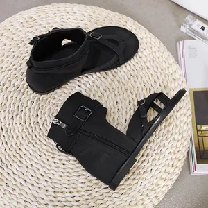 Detailed view of black women's gladiator sandals with zipper and buckle on straw mat