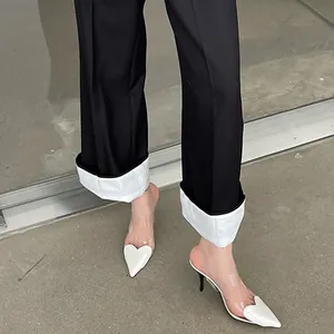 Dettaglio di sabot trasparenti a punta con tacco alto e decorazione a cuore bianco elegante.