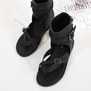 Detailed view of stylish black Roman sandals with ankle straps and buckle details on white surface