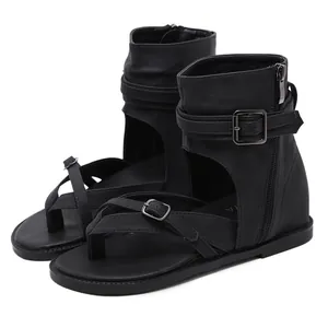 Close-up detail of black Roman gladiator sandals featuring ankle straps and metal buckles