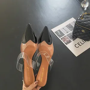Primo piano della punta nera a forma di cuore su scarpe trasparenti con tacco alto.