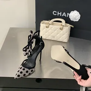 Nahaufnahme eleganter Polka-Dot-Mesh-Sandaletten mit hohem Absatz und Schleifendetail.