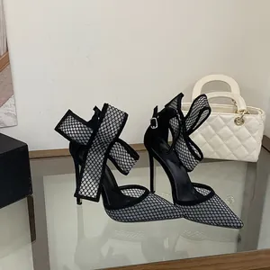 Detailansicht eleganter schwarzer Mesh-Stilettos mit großer Schleife am Knöchel.
