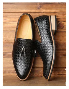 Elegante Herren-Loafer aus schwarzem Flechtleder mit Quasten auf rustikalen Holzbohlen