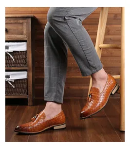 Detailansicht brauner Leder-Slipper mit Webmuster, Zierquasten und strukturierter Oberfläche.