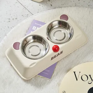 Cute bear-themed double pet bowl with stainless steel inserts on cream-colored base.