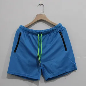 Detalle de pantalones cortos deportivos azules para hombre con cordón verde y bolsillos