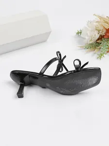 Detaillierte Seitenansicht eleganter schwarzer Kitten-Heel-Pantolette mit Schleifenverzierung.