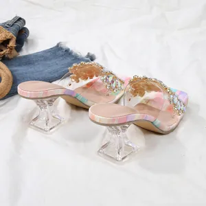 Detailweergave van zomerse strass-sandalen met transparante architecturale kristalhakken.